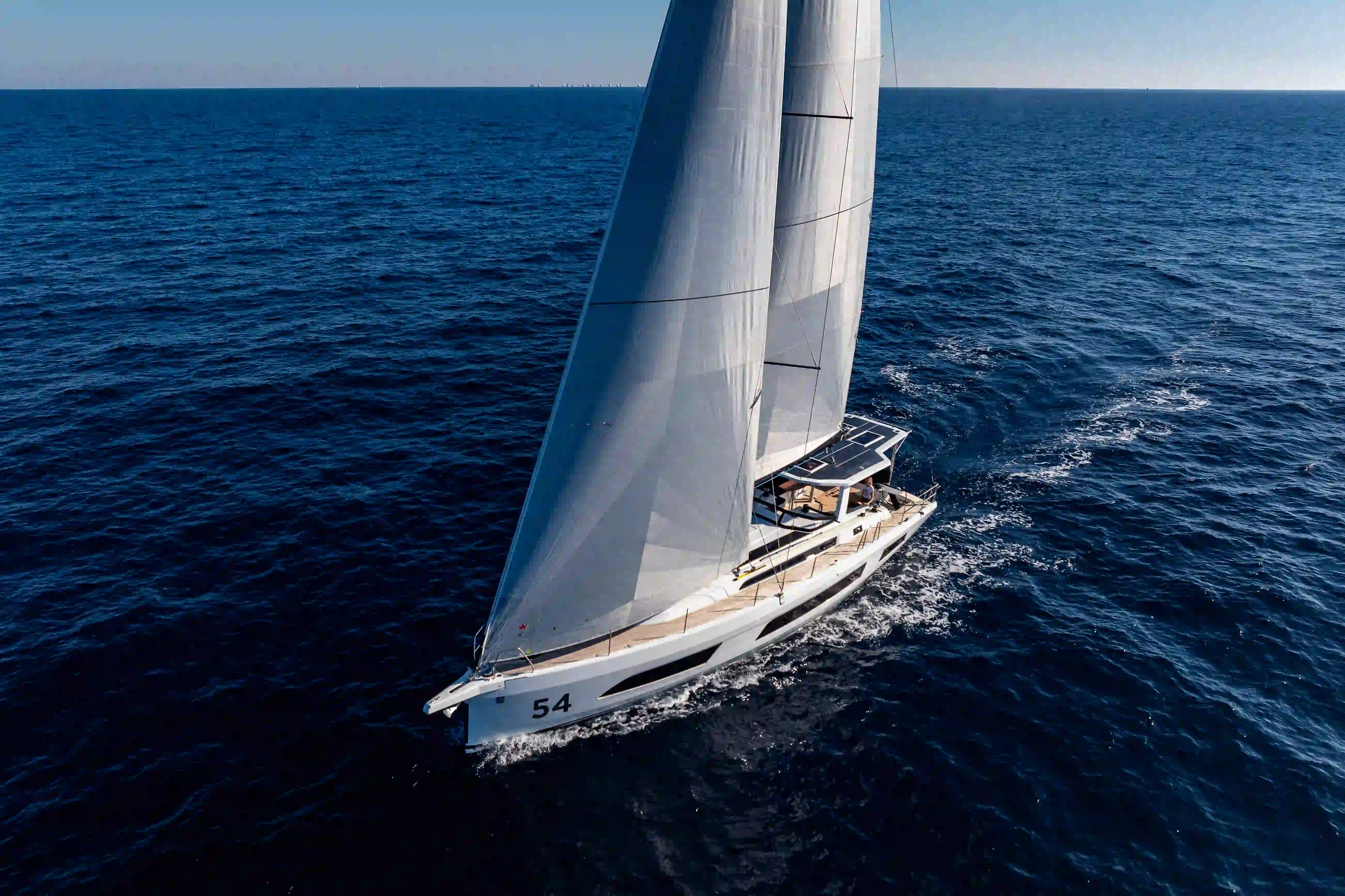Hybrid Dufour 54 sailing offshore, viewed from above, highlighting smooth navigation, balanced sailing performance, and open-sea cruising comfort