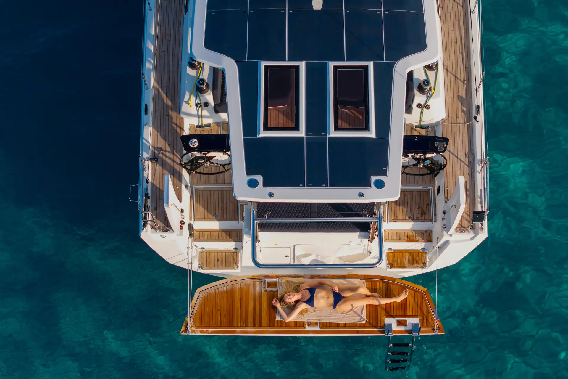Hybrid Dufour 54 at anchor seen from above, showcasing solar panels, aft platform relaxation, and a calm, comfortable onboard lifestyle joool